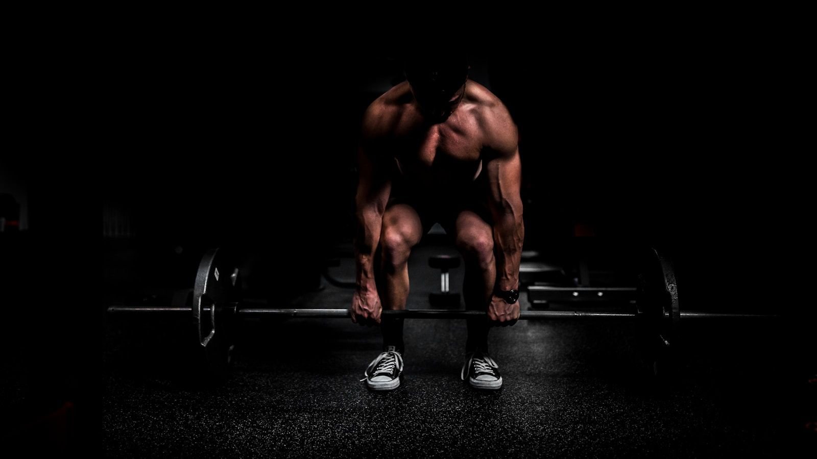 Member setting up for a heavy deadlift under dramatic lighting