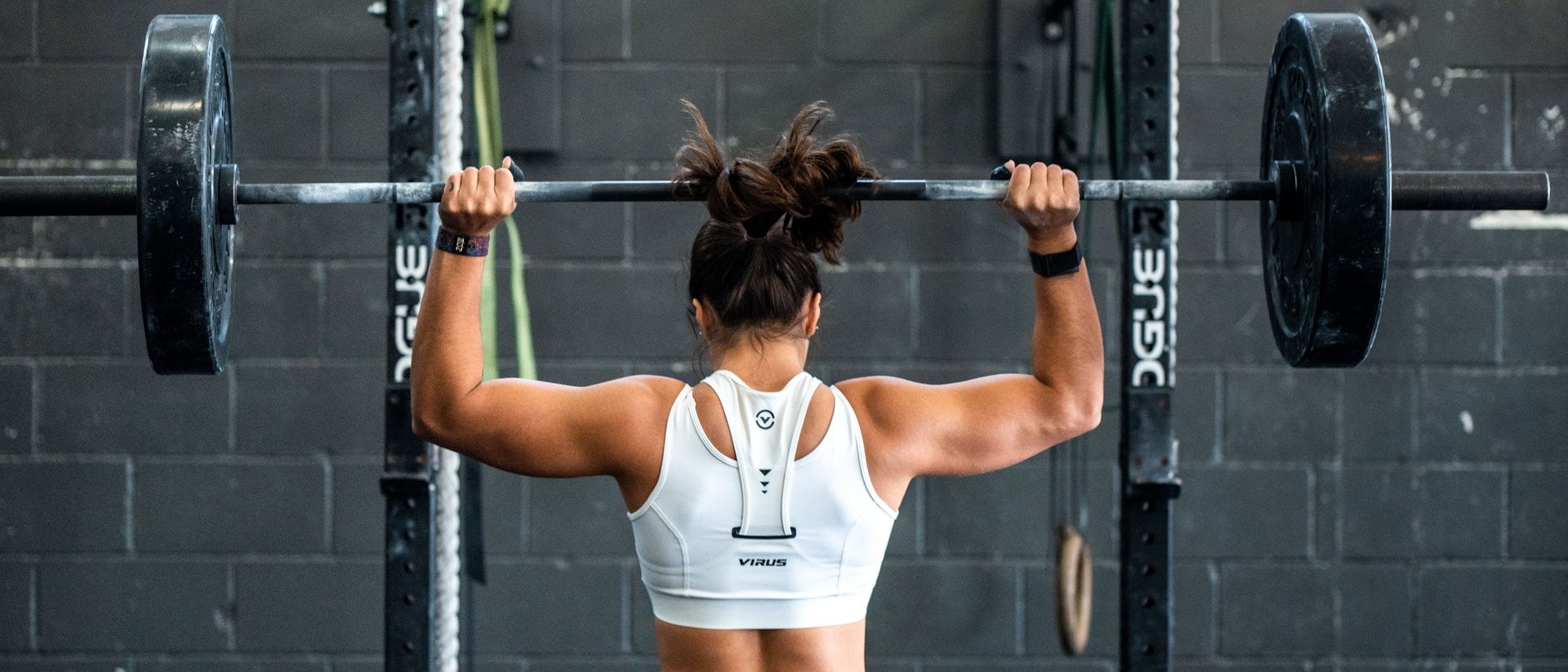Member pressing a barbell overhead during a strength session